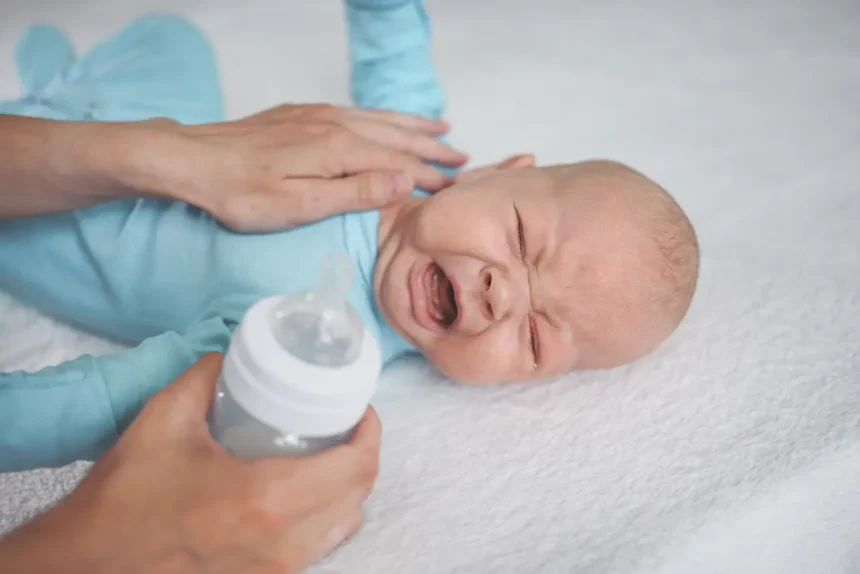 cute-emotional-crying-newborn-boy-laying-bed-with-milk-bottle